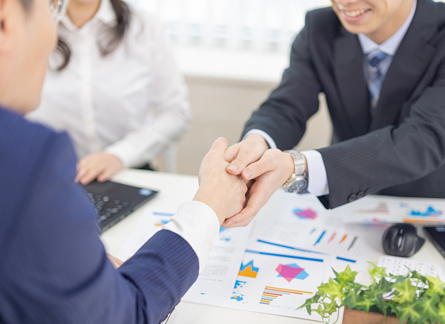 Business people shaking hands over a meeting table